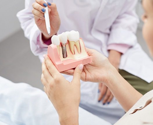 Woman holding 3-D model of dental implant structure