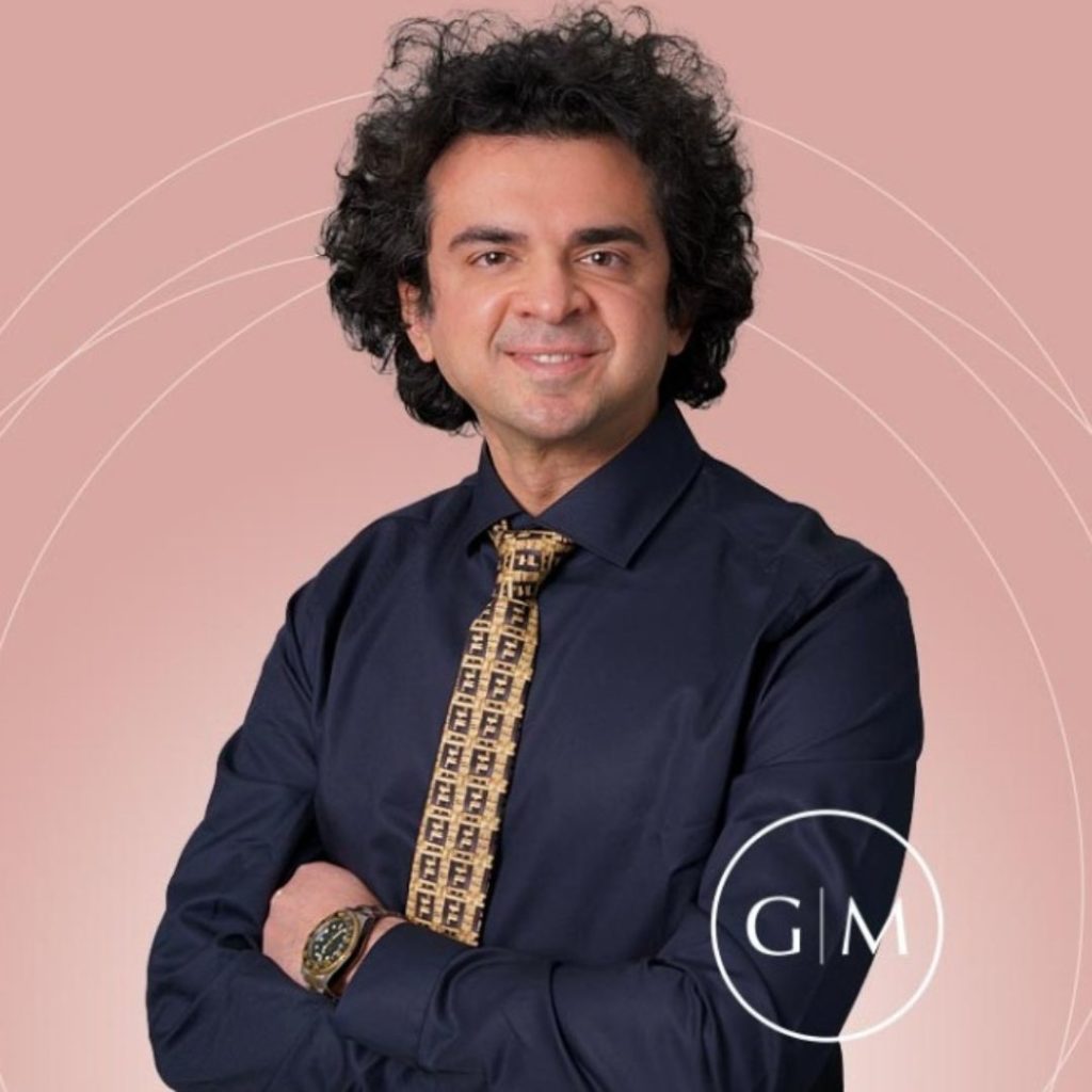 Dr. Reza smiling with crossed arms with pink background
