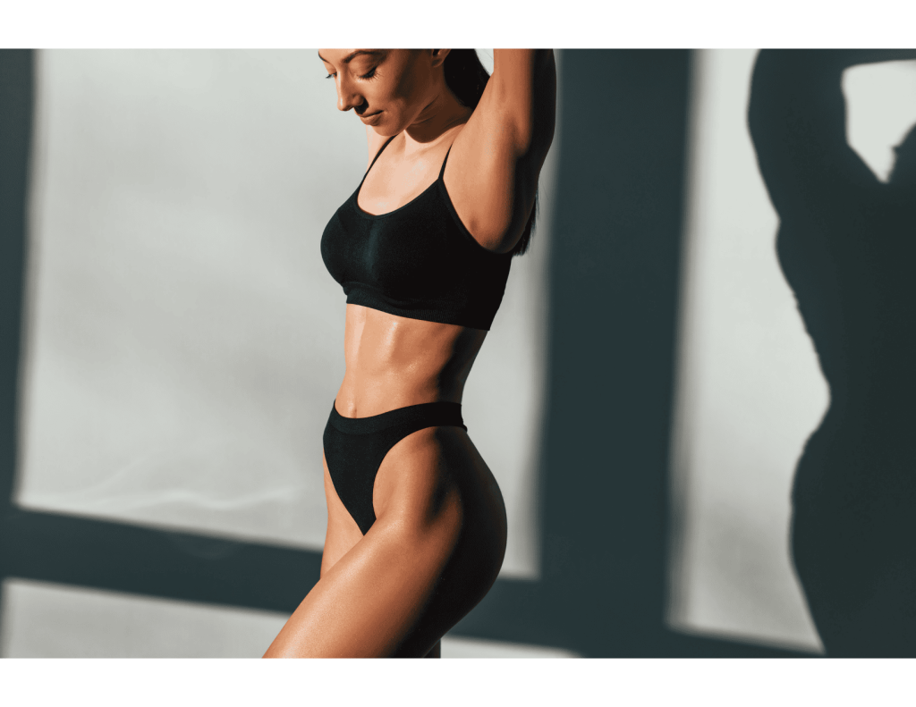 Athletic woman in black set, side profile with defined waist and flat abdomen—common mommy makeover goals.