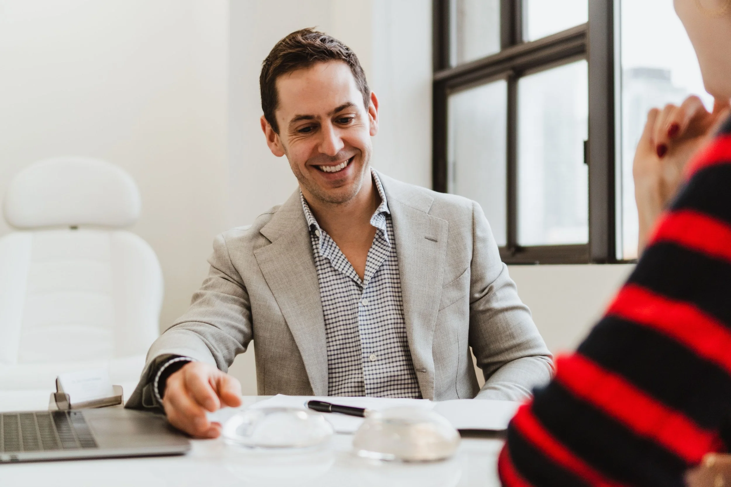 Dr. Alex Viezel-Mathieu, Montreal plastic surgeon, smiling in clinic; expert in mommy makeover procedures.